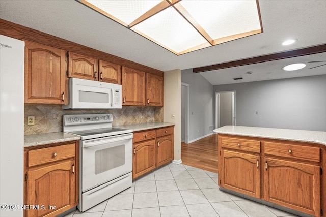 kitchen featuring brown cabinetry, white appliances, light countertops, tasteful backsplash, and light tile patterned floors