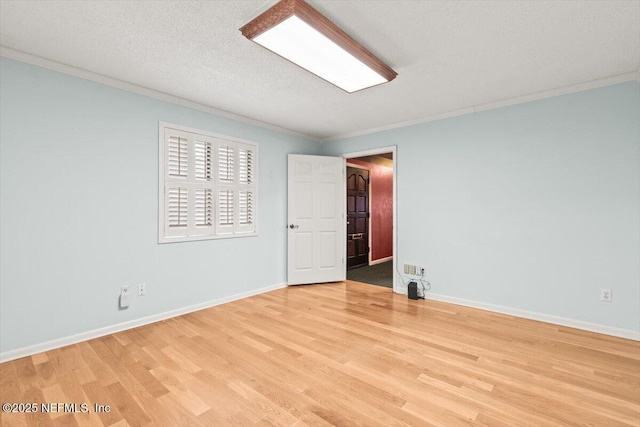 spare room featuring crown molding, light wood-style flooring, and baseboards