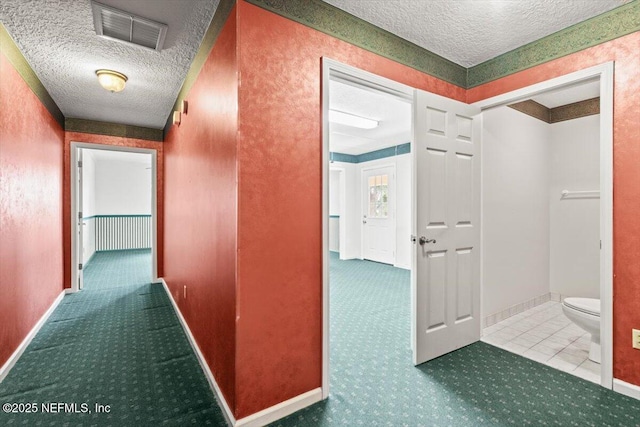 corridor featuring visible vents, carpet flooring, and a textured ceiling