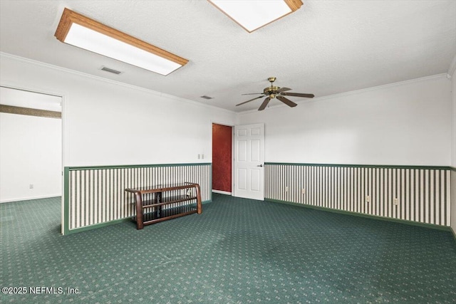 empty room featuring visible vents, crown molding, carpet floors, baseboards, and ceiling fan