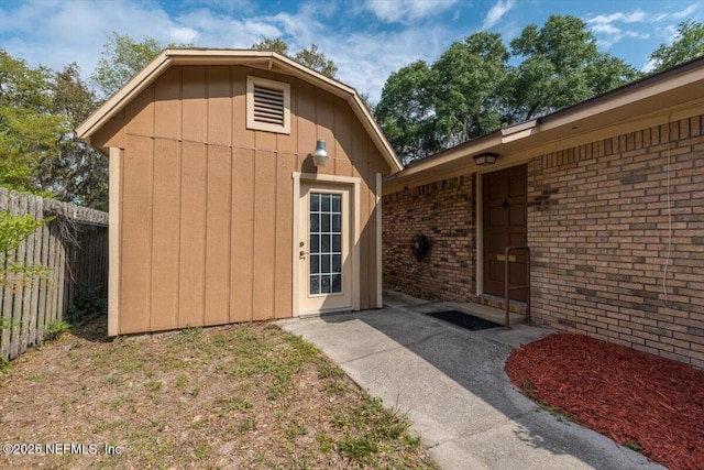 doorway to property featuring brick siding and fence