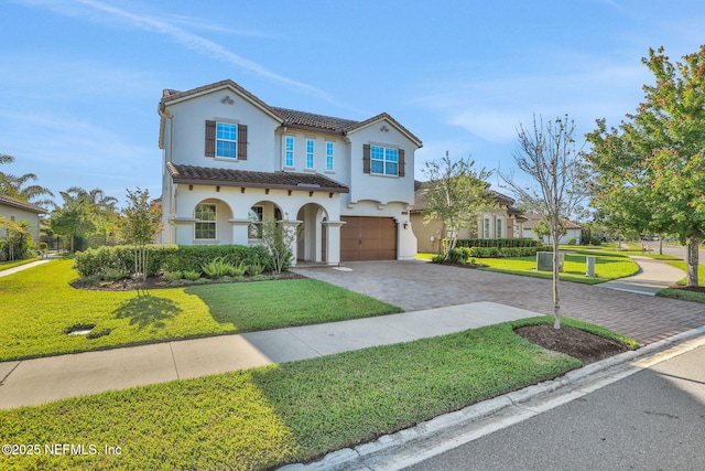 mediterranean / spanish home with a tile roof, decorative driveway, a front yard, stucco siding, and a garage
