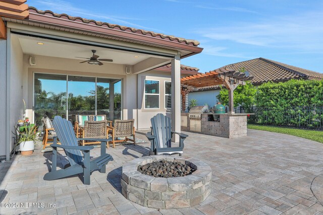 view of patio / terrace featuring a pergola, exterior kitchen, area for grilling, a ceiling fan, and a fire pit