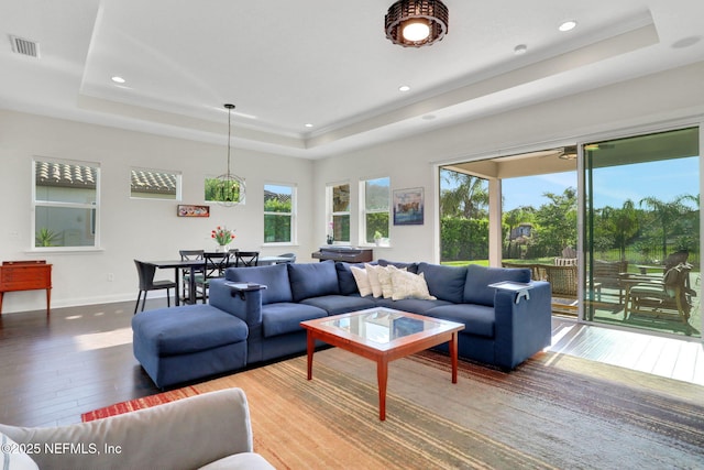 living room featuring hardwood / wood-style floors, visible vents, a healthy amount of sunlight, and a tray ceiling