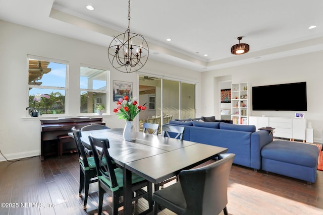 dining space featuring a tray ceiling, baseboards, an inviting chandelier, wood-type flooring, and recessed lighting