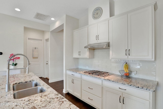 kitchen with stainless steel gas cooktop, a sink, decorative backsplash, under cabinet range hood, and visible vents
