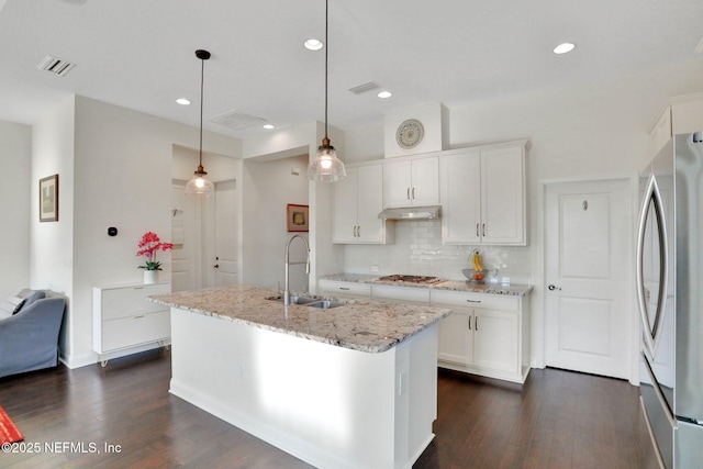 kitchen with a sink, under cabinet range hood, stainless steel appliances, white cabinetry, and dark wood finished floors