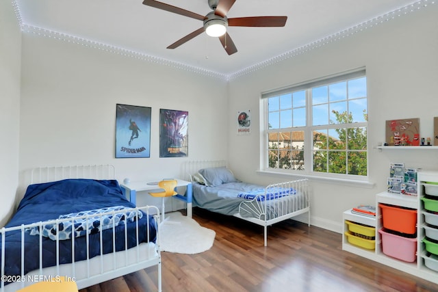 bedroom featuring baseboards, wood finished floors, and a ceiling fan