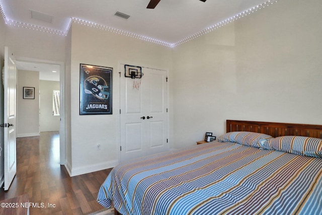 bedroom featuring a closet, ceiling fan, visible vents, baseboards, and wood finished floors