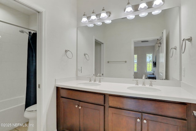 bathroom featuring shower / bath combination with curtain, toilet, double vanity, and a sink