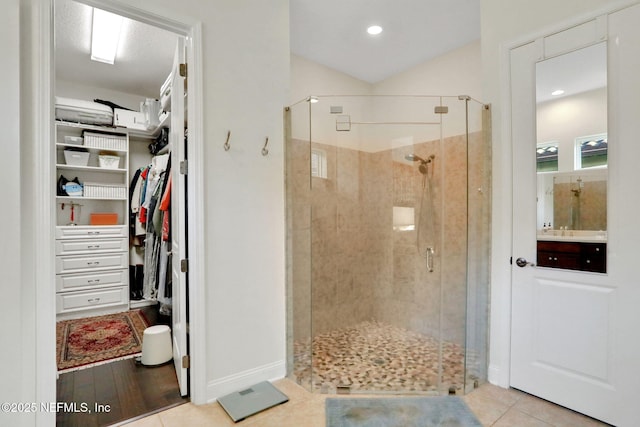 bathroom with a sink, a stall shower, baseboards, tile patterned flooring, and a spacious closet