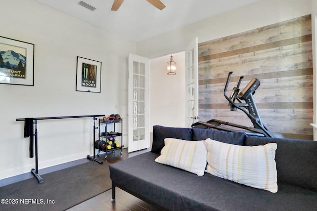 interior space featuring wood walls, visible vents, french doors, wood finished floors, and a ceiling fan