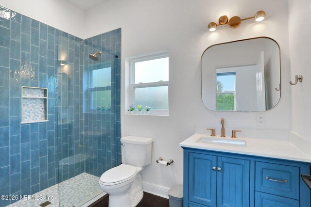 bathroom featuring toilet, tiled shower, and vanity