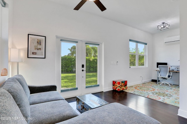 living room featuring wood finished floors, ceiling fan, a wall mounted AC, baseboards, and french doors