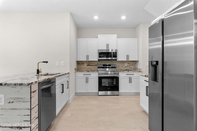 7708 Galveston Ave, Jacksonville, FL 32211 - kitchen featuring light stone countertops, a sink, backsplash, white cabinetry, and appliances with stainless steel finishes