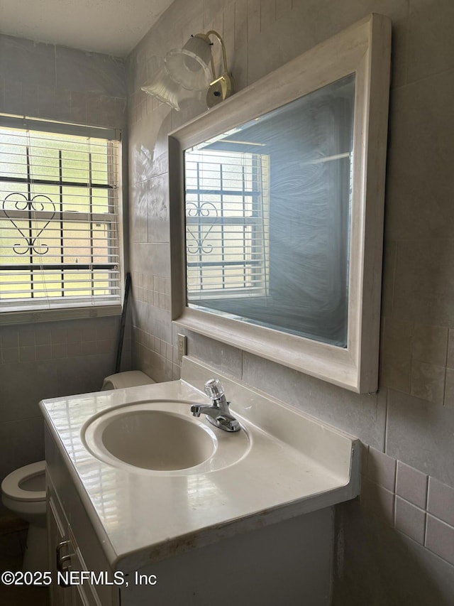 bathroom with toilet, tile walls, and vanity