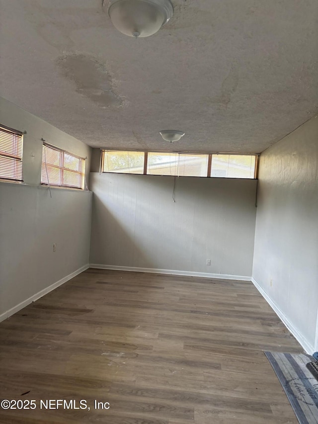 spare room with baseboards, wood finished floors, and a textured ceiling