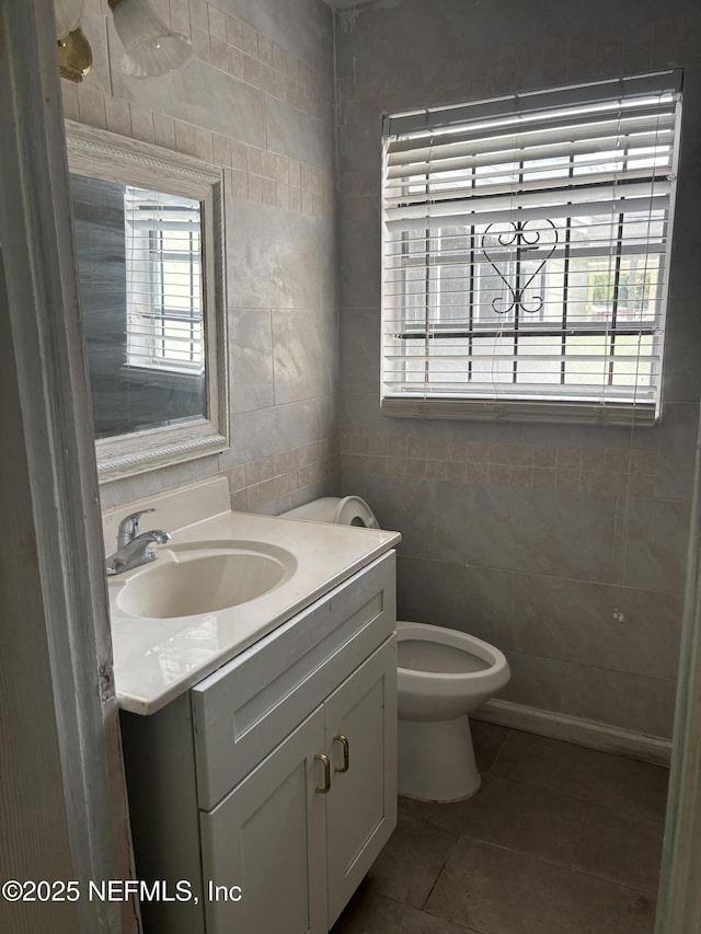 bathroom featuring a healthy amount of sunlight, vanity, tile patterned flooring, and tile walls