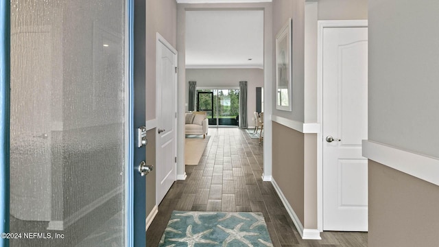 hallway with crown molding, dark wood-style flooring, and baseboards