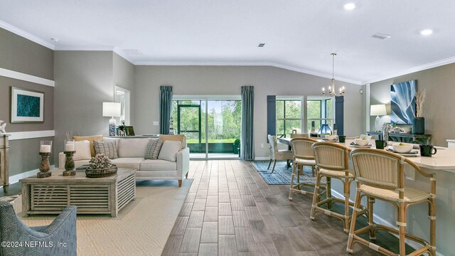 living area with a chandelier, wood finished floors, crown molding, visible vents, and lofted ceiling