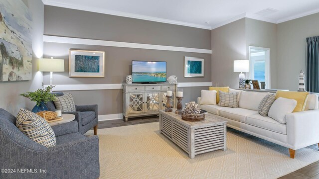 living area with baseboards, visible vents, wood finished floors, and ornamental molding