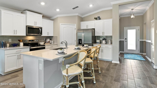 kitchen featuring decorative backsplash, a breakfast bar, appliances with stainless steel finishes, a sink, and visible vents