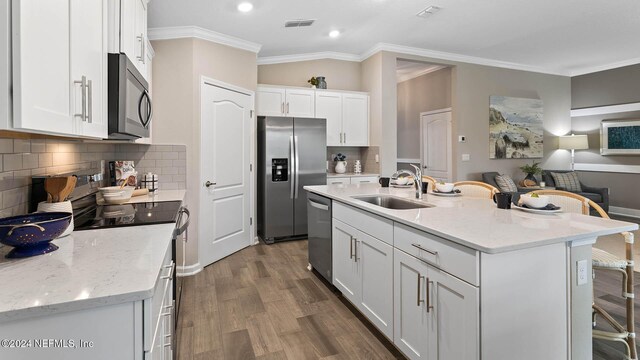 kitchen featuring ornamental molding, a sink, stainless steel appliances, and visible vents
