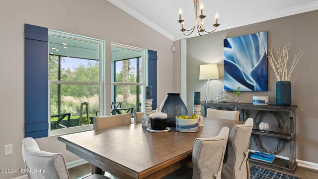 dining space with a chandelier, wood finished floors, crown molding, baseboards, and lofted ceiling