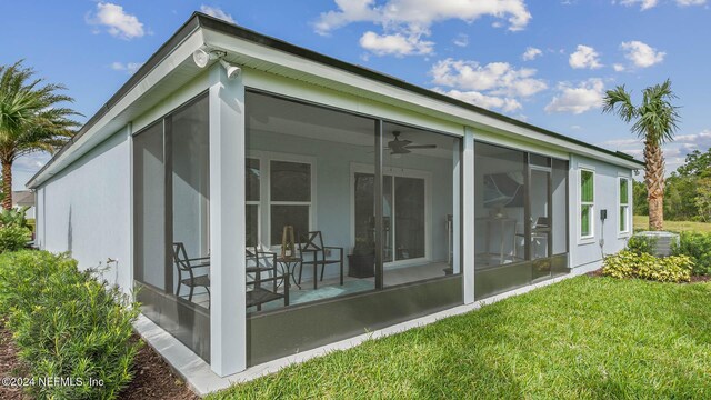 rear view of house featuring a yard, a ceiling fan, and a sunroom