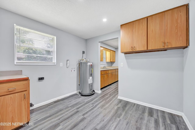 4043 Marland St, Jacksonville, FL 32209 - clothes washing area with light wood finished floors, a sink, baseboards, and electric water heater