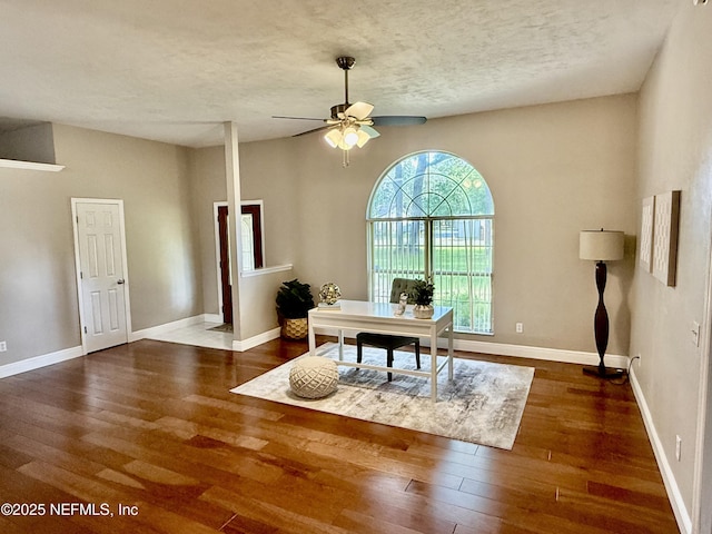home office with a textured ceiling, ceiling fan, hardwood / wood-style flooring, and baseboards