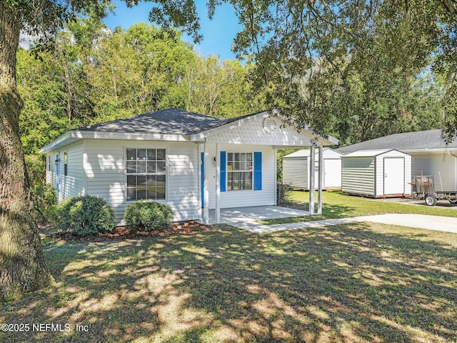 bungalow-style home featuring an outdoor structure, a storage unit, a shingled roof, covered porch, and a front yard