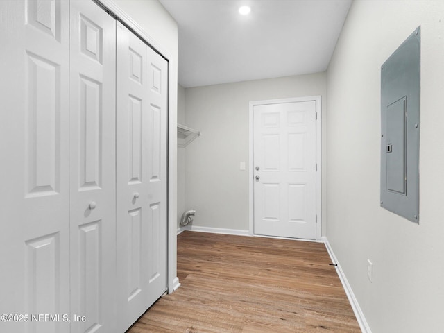 laundry room with baseboards, electric panel, and light wood finished floors