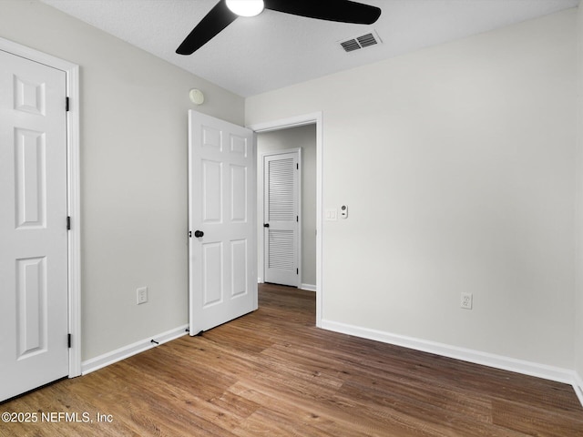 unfurnished bedroom with wood finished floors, visible vents, and baseboards