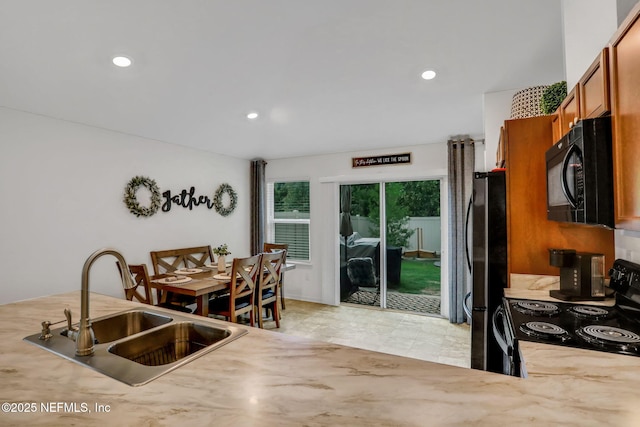 kitchen with a sink, brown cabinetry, black appliances, and recessed lighting