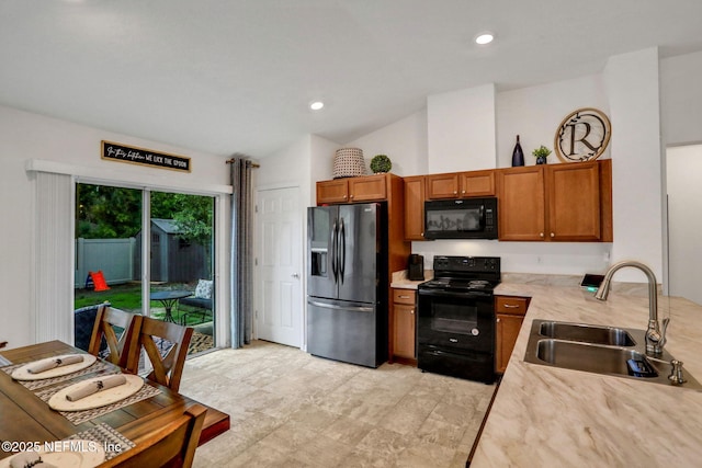 kitchen with brown cabinets, lofted ceiling, a sink, and black appliances