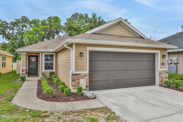 view of front of home with concrete driveway, an attached garage, a shingled roof, and stone siding
