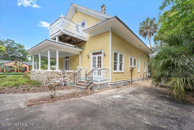 223 Rainey Ave, Saint Augustine, FL 32084 - view of front facade with a balcony, a chimney, and covered porch