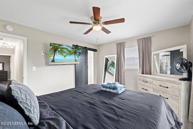 bedroom with a barn door and a ceiling fan