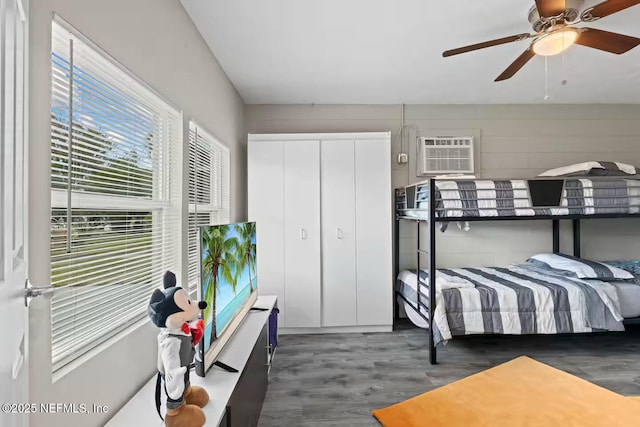 bedroom with multiple windows, wood finished floors, and a wall unit AC