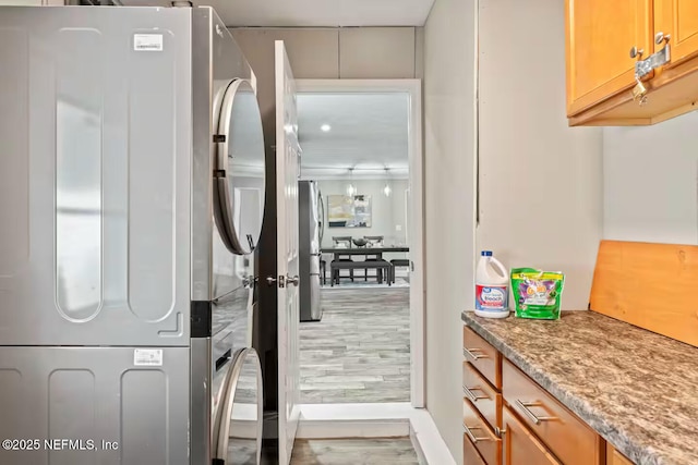 interior space with light wood finished floors and stacked washer / dryer