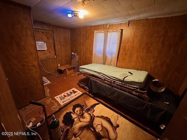 bedroom featuring wooden walls and a wall mounted AC