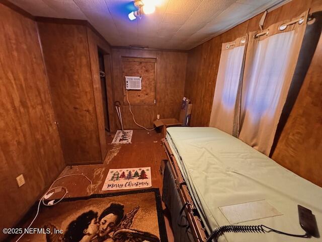 bedroom with wooden walls and a wall mounted AC