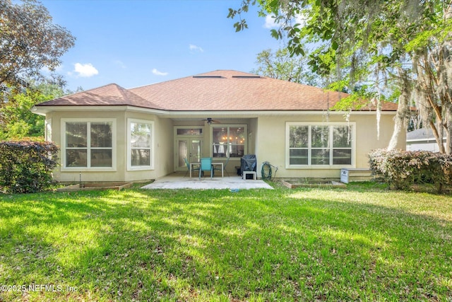 back of property with a ceiling fan, a yard, stucco siding, and a patio area