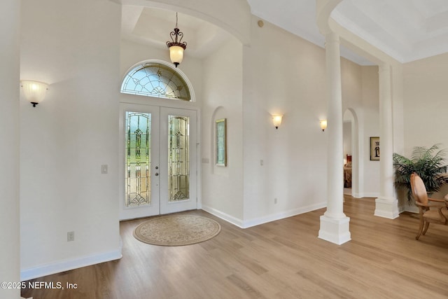 entryway with wood finished floors, arched walkways, baseboards, and a high ceiling