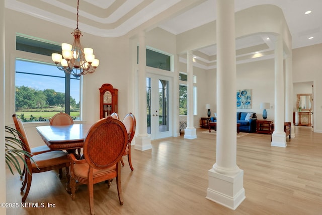 dining area featuring a healthy amount of sunlight, light wood-type flooring, and a towering ceiling
