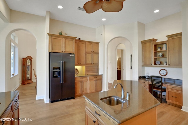 kitchen with ceiling fan, open shelves, a sink, high end black fridge, and arched walkways
