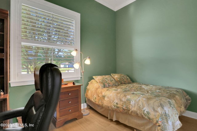 bedroom featuring crown molding, baseboards, and light wood-style flooring