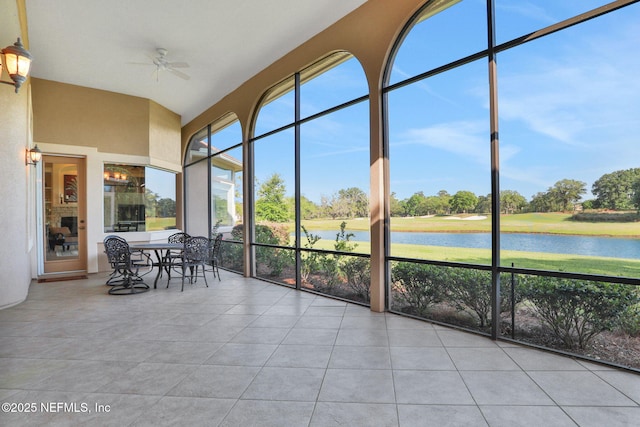 sunroom featuring a water view, ceiling fan, and tile patterned flooring