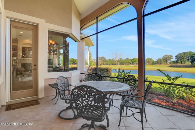 sunroom featuring tile patterned floors, a water view, and outdoor dining area